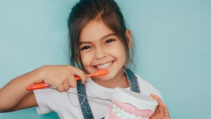 girl smiling while brushing her teeth